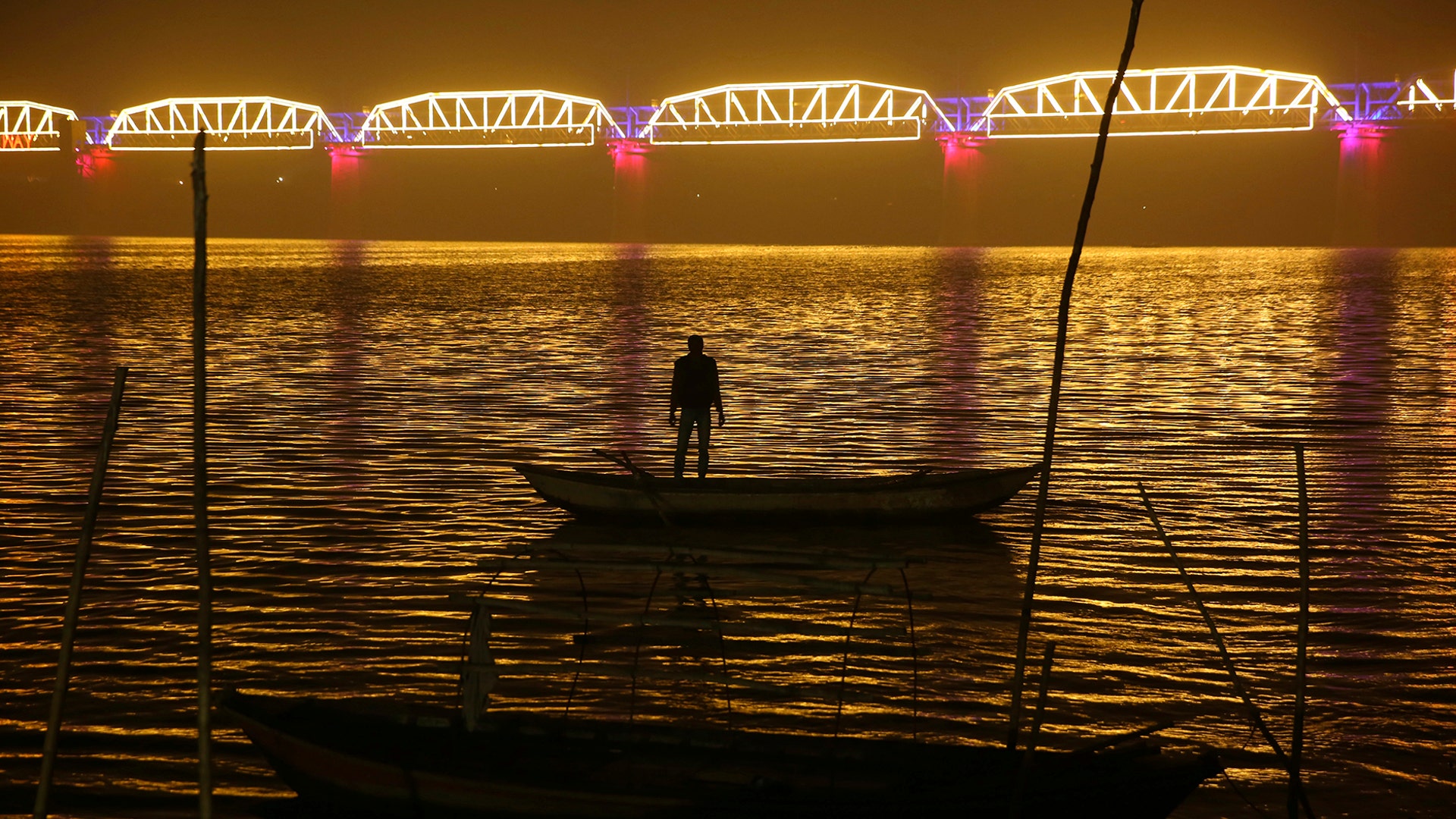 A person looks at an illuminated railway bridge across the river Yamuna ahead of the upcoming Kumbh Mela festival in Allahabad, India, Dec. 31, 2018. 
