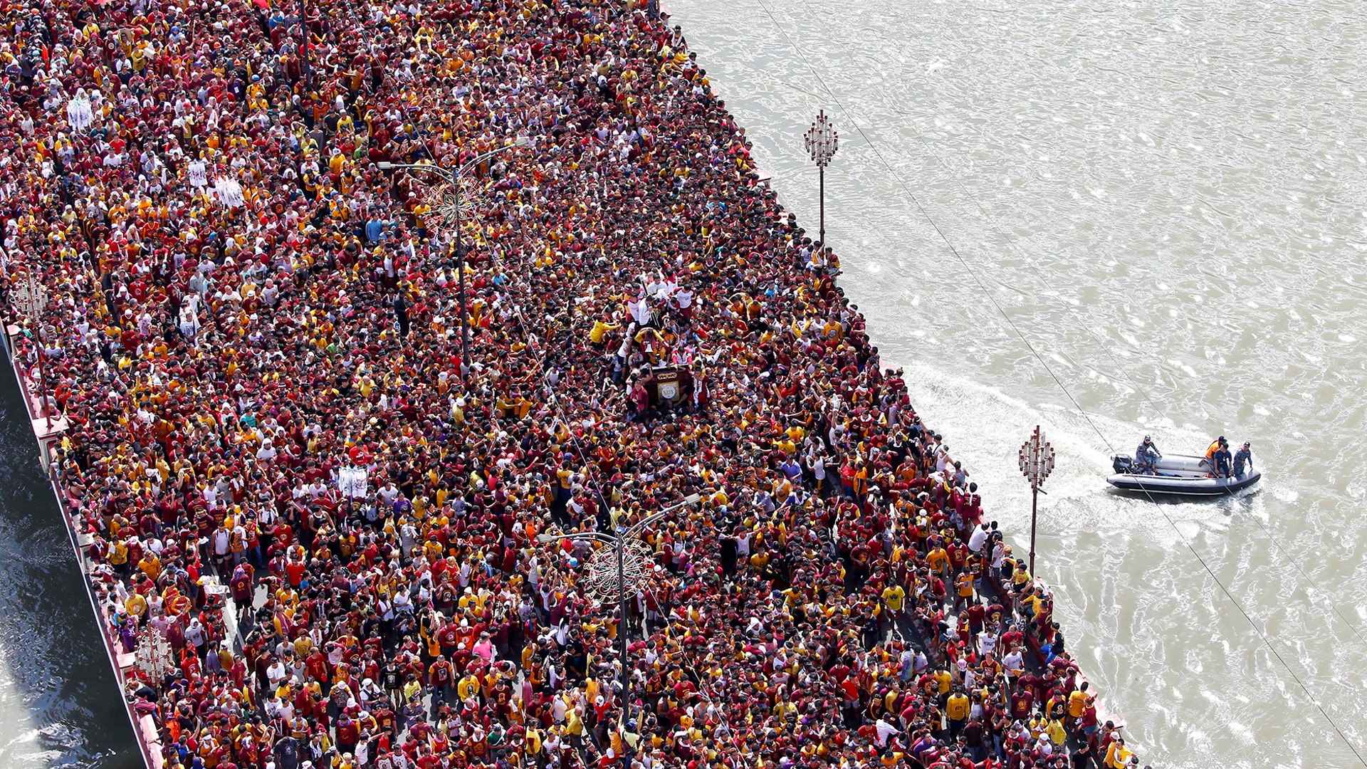 Philippine Coast Guard members keep watch as Roman Catholic devotees cross a bridge in a procession of the Black Nazarene to celebrate its feast day in Manila, Jan. 9, 2019. 
