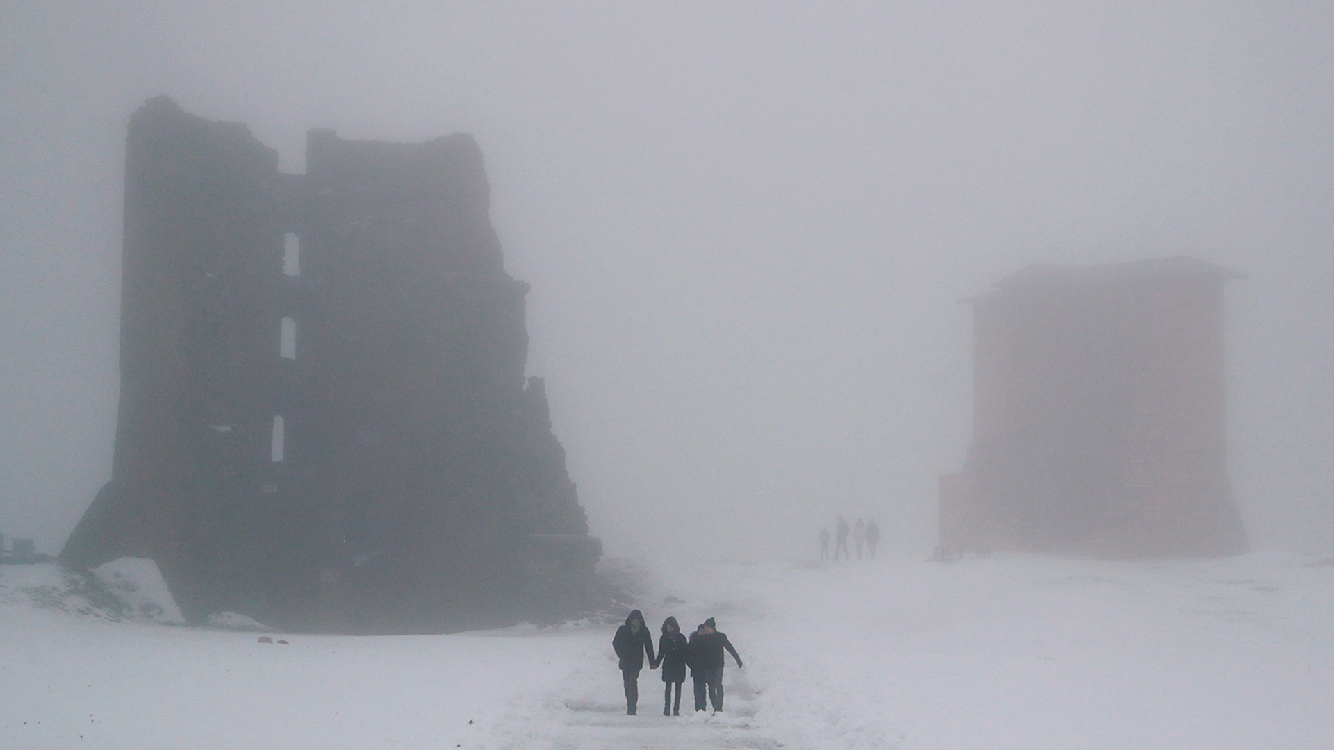 People walk past the ruins of a medieval castle on a foggy day in the Belarusian town of Novogrudok, Dec. 30, 2018. 