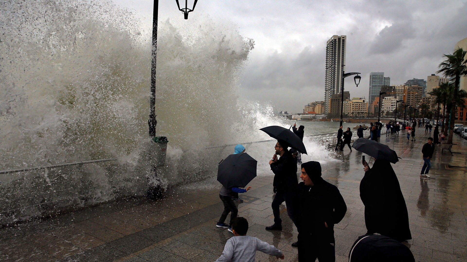 Residents play in front of waves crashing into the seawall in Beirut, Lebanon, Jan. 6, 2019. 