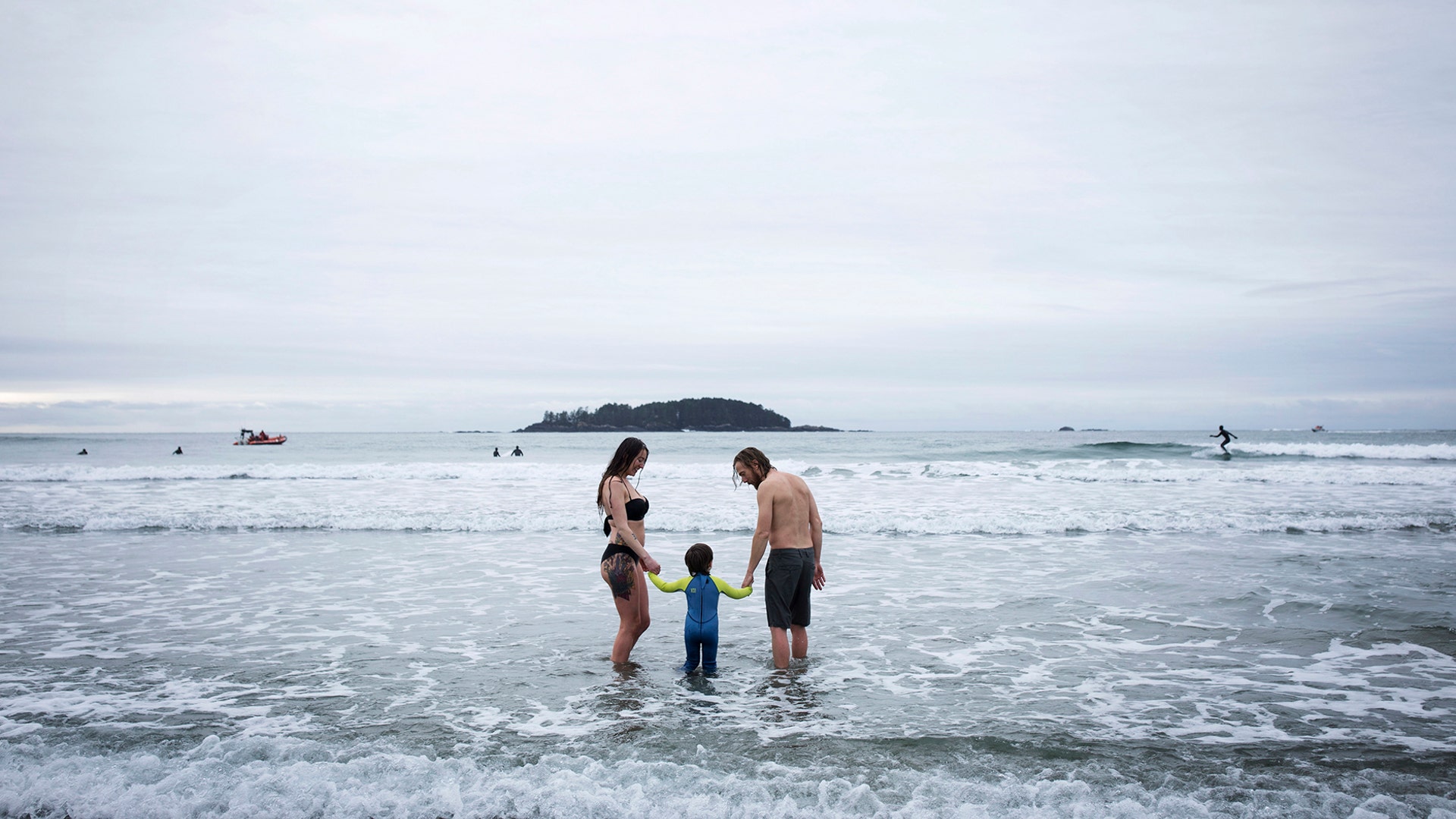Clio O'Connell and Jeff Chrisholm hold hands with 3-year-old Torin O'Connell after the annual polar bear swim on Chesterman Beach in Tofino, British Columbia, Jan. 1, 2019. 