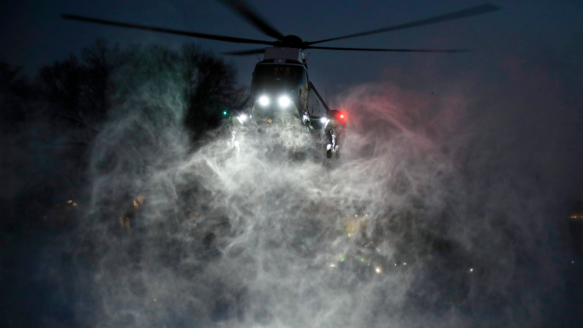 Snow is kicked up by the prop wash from the Marine One helicopter carrying President Trump, as it hovers over the snow-covered South Lawn landing at the White House, Jan. 14, 2019. 