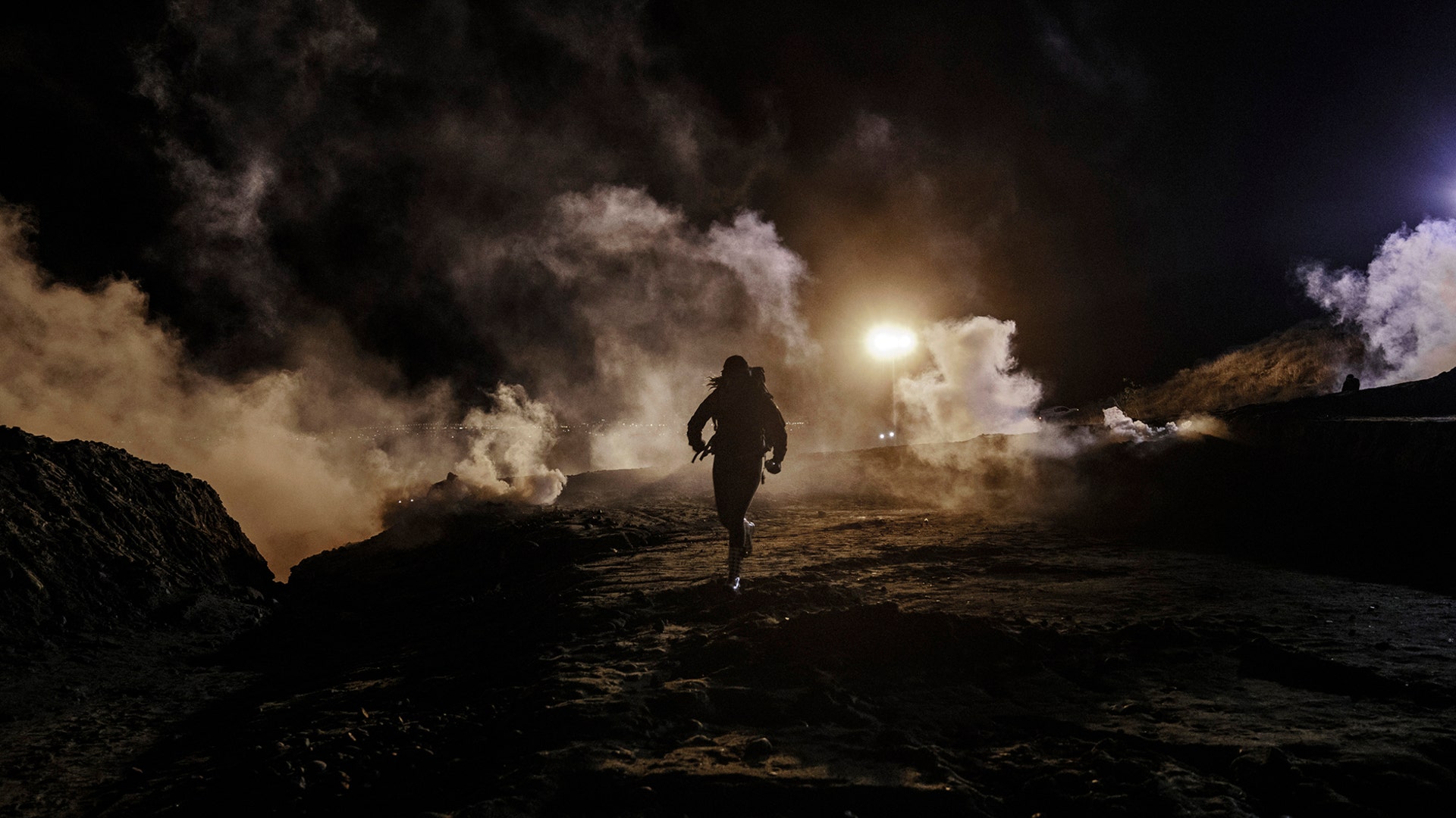 Migrants run as U.S. Border Protection officers throw tear gas to the Mexican side of the border fence after they climbed the fence to get to San Diego, from Tijuana, Mexico, Jan. 1, 2019. 