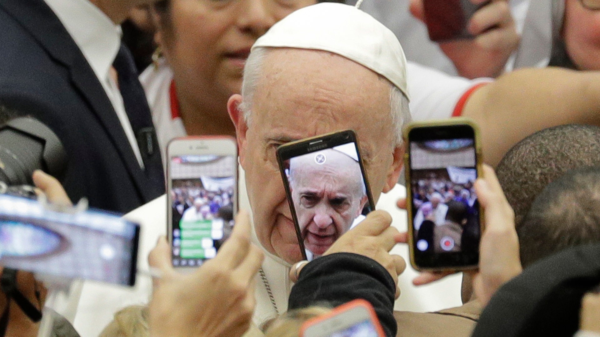 Pope Francis is framed by cellphones as he arrives for his weekly general audience, in the Pope Paul VI hall, at the Vatican, Jan. 9, 2019. 
