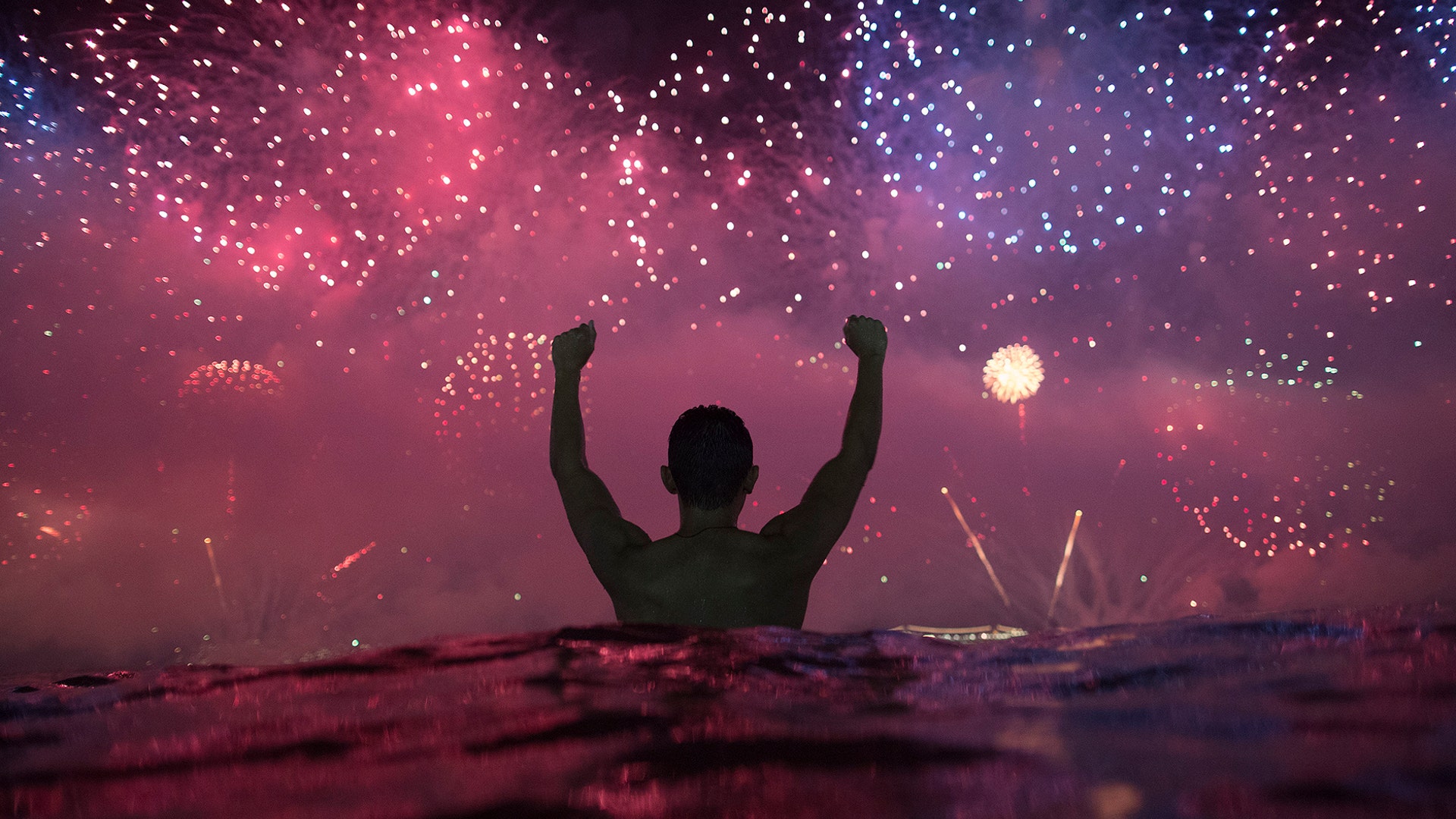 A man watches the fireworks exploding over Copacabana Beach during the New Year's celebrations in Rio de Janeiro, Brazil, Jan. 1, 2019. 