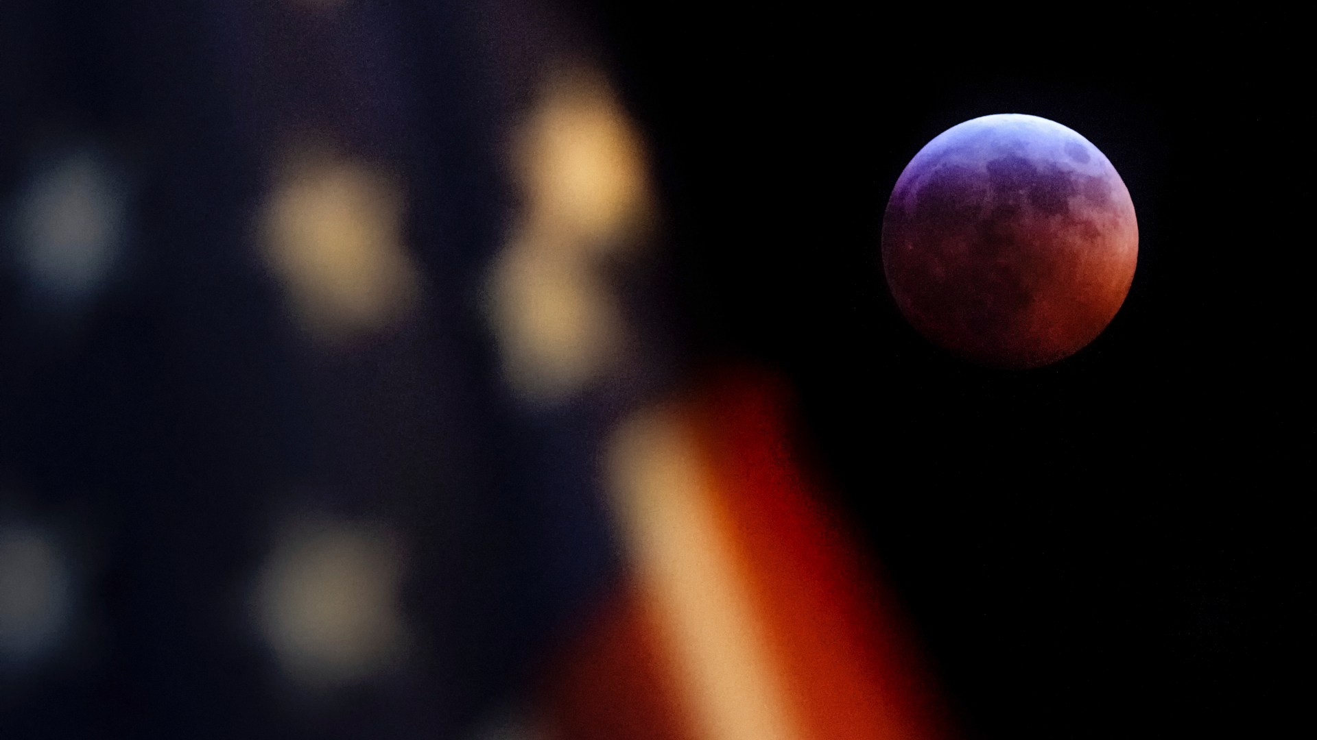 The super blood Moon is the last total lunar eclipse until May 26, 2021. In this photo a U.S. Flag in downtown Washington flies in front of the moon during the lunar eclipse, Sunday, Jan. 20, 2019.