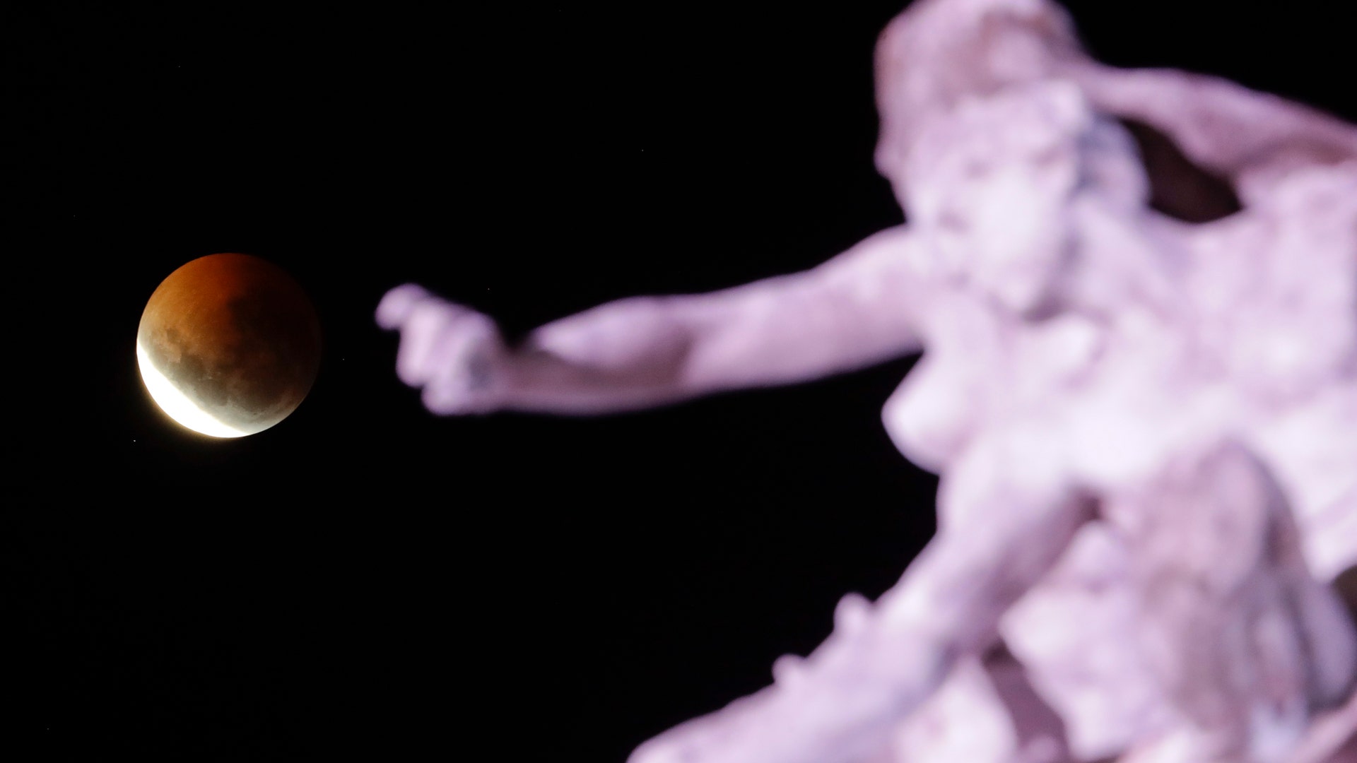 The stunning super blood Moon lunar eclipse visible behind the "Monumento a la Carta Magna y Las Cuatro Regiones Argentinas" in Buenos Aires, Argentina, Monday, Jan. 21, 2019.