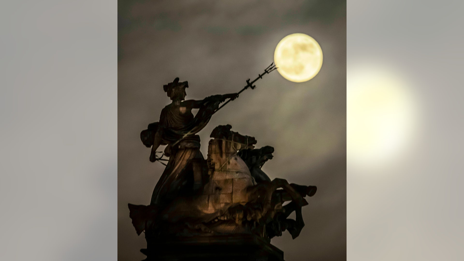 The supermoon rises above the 'Maritime Prowess' statue by Albert Hemstock Hodge on the Guild Hall ahead of the Lunar Eclipse, in Hull, England, Sunday, Jan. 20, 2019.
