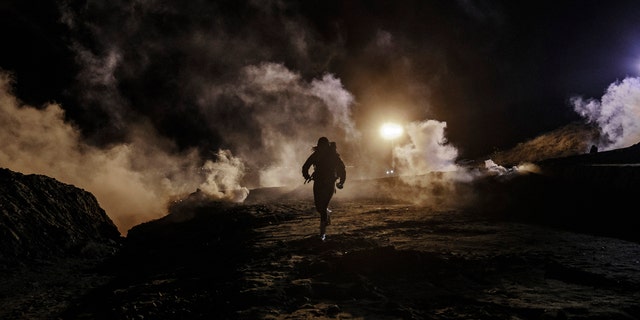 Migrants run as tear gas is thrown by U.S. Border Protection officers to the Mexican side of the border fence after they climbed the fence to get to San Diego, Calif., from Tijuana, Mexico, Tuesday, Jan. 1, 2019. Discouraged by the long wait to apply for asylum through official ports of entry, many migrants from recent caravans are choosing to cross the U.S. border wall and hand themselves in to border patrol agents. (AP Photo/Daniel Ochoa de Olza)