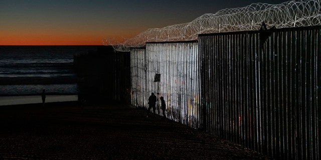 The sun sets while people get close to the border fence between the U.S. side of San Diego, Calif., and Tijuana, in Mexico, Wednesday, Jan. 2, 2019.