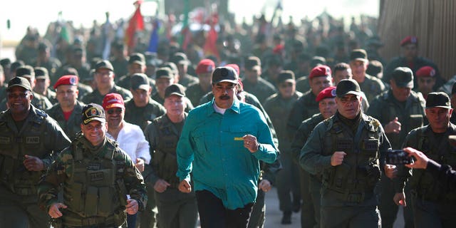 In this photo released to the media by Miraflores presidential palace press office, Venezuelan President Nicolas Maduro, center, jogs alongside his Defense Minister Vladimir Padrino Lopez, right, and soldiers as he visits Ft. Paramacay in Carabobo state, Venezuela, Sunday, Jan. 27.