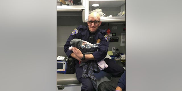 California Highway Patrol Officer Jeffrey Lloyd holds a baby he helped deliver along Highway 99 on Monday. (CHP South Sacramento)