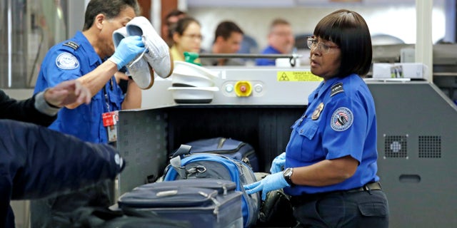 Transportation Security Administration (TSA) officers assist travelers with luggage through a security screening area during a partial federal government shutdown Monday, Dec. 31, 2018, at Seattle-Tacoma International Airport in Washington state. (Associated Press)