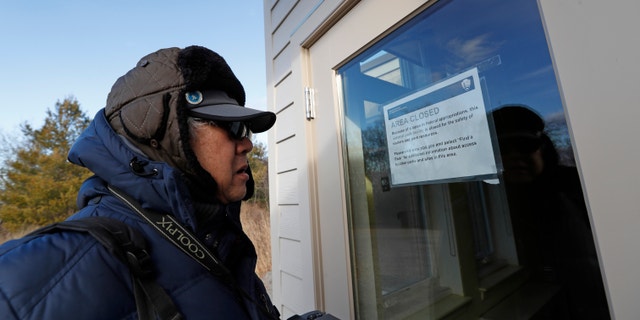 A New York resident is seen reading a notification announcing the temporary closure of a visitor's center at a Wildlife Refuge in Queens, N.Y., on Jan. 3.