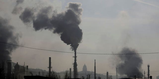 In this Dec. 10, 2018 photo, smokestacks near an oil refinery are seen in front of the Utah State Capitol as an inversion settles over Salt Lake City. Inversions hover over Salt Lake City as cold, stagnant air settles in the bowl-shaped mountain basins, trapping tailpipe and other emissions that have no way of escaping to create a brown, murky haze the engulfs the metro area. Doctors warn that breathing the polluted air can cause lung problems and other health concerns, especially for pregnant women and people with respiratory issues. (AP Photo/Rick Bowmer)