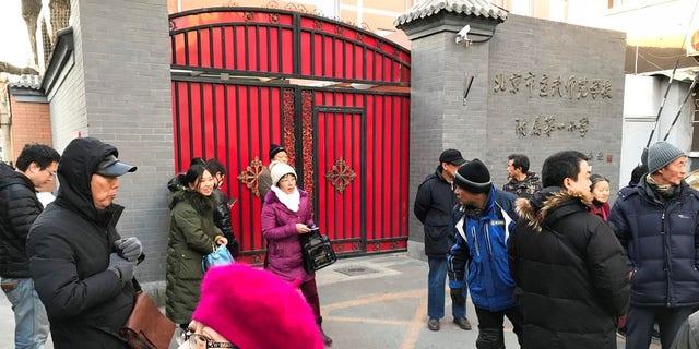 Parents gather at an entrance gate to the Beijing No. 1 Affiliated Elementary School of Xuanwu Normal School following an attack in Beijing, China, Tuesday, Jan. 8, 2019.