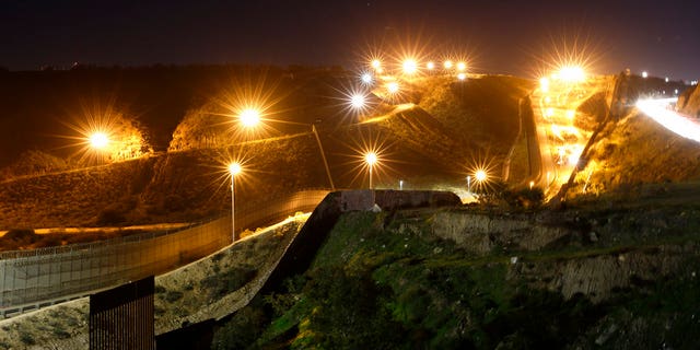 FILE - In this Monday, Jan. 7, 2019, file photo, floodlights from the U.S, illuminate multiple border walls, seen from Tijuana, Mexico. (AP Photo/Gregory Bull, File)