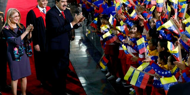 Venezuela's President Nicolas Maduro and first lady Cilia Flores stop to greet flag-waving children upon arrival to the Supreme Court for Maduro's inauguration ceremony in Caracas, Venezuela, Thursday, Jan. 10, 2019.