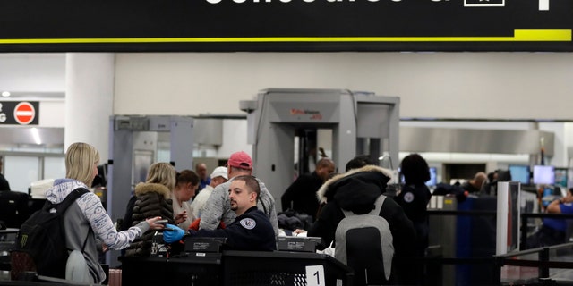 A Transportation Security Administration officer works at the entrance to Concourse G at Miami International Airport, Friday, Jan. 11, 2019, in Miami. The airport is closing Terminal G this weekend as the federal government shutdown stretches toward a fourth week because security screeners have been calling in sick at twice the airport's normal rate. (AP Photo/Lynne Sladky)