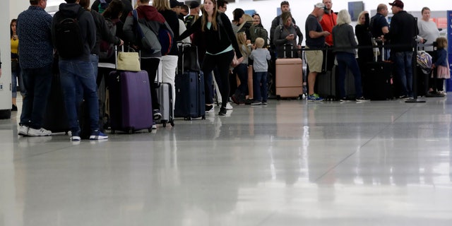Passengers wait in line at Sun Country Airlines in Terminal G at Miami International Airport, Friday, Jan. 11, 2019, in Miami. The airport is closing Terminal G this weekend as the federal government shutdown stretches toward a fourth week because security screeners have been calling in sick at twice the airport's normal rate. (AP Photo/Lynne Sladky)