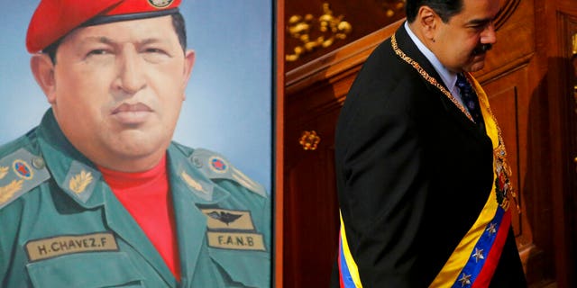 Venezuela's President Nicolas Maduro walks past a painting of his predecessor, late President Hugo Chavez, inside the chambers of the Constitutional Assembly where he will give his annual address to the nation in Caracas, Venezuela, Monday, Jan. 14, 2019.