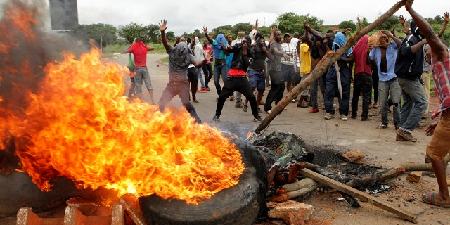 In this Tuesday, Jan. 15, 2019 file photo, protestors gather near a burning tire during a demonstration over the hike in fuel prices in Harare, Zimbabwe. 2019 is already a busy year for internet shutdowns in Africa, with governments ordering cutoffs as soon as a crisis appears. Zimbabwe ordered a “total internet shutdown” in recent days during protests over a dramatic fuel price increase and a resulting deadly crackdown.