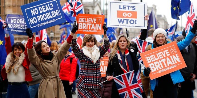 Leavers hold up signs next to pro-European demonstrators protesting opposite the Houses of Parliament in London, Tuesday, Jan. 15, 2019. Britain's Prime Minister Theresa May is struggling to win support for her Brexit deal in Parliament. Lawmakers are due to vote on the agreement Tuesday, and all signs suggest they will reject it.