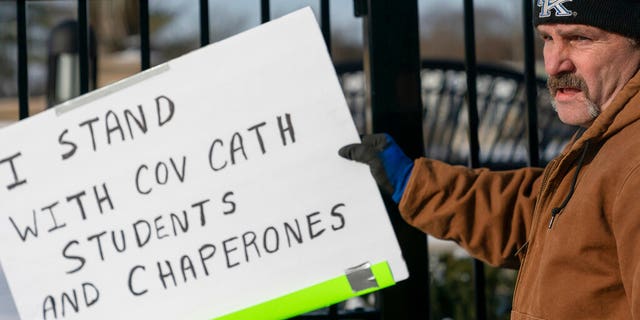 A man places a sign showing support for the students of Covington Catholic Catholic High School in front of the Catholic Diocese of Covington in Covington, Ky., Tuesday, Jan 22, 2019. [AP Photo/Bryan Woolston)