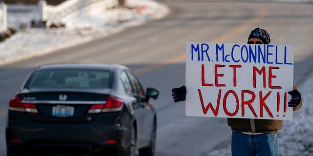 Furloughed EPA worker Jeff Herrema holds a sign outside the offices of U.S. Senator Mitch McConnell, in Park Hills, Ky., Tuesday, Jan 22, 2019. (AP Photo/Bryan Woolston)