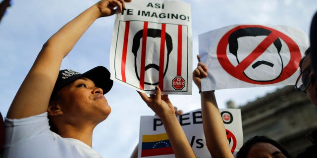 Venezuelan anti-government protesters hold signs against Venezuelan President Nicolas Maduro during a demonstration in Buenos Aires, Argentina, Wednesday, Jan. 23, 2019. Hundreds of people, mostly Venezuelan migrants, held a rally against Maduro and in favor of Juan Guaido, head of Venezuela's opposition-run congress who today proclaimed himself president of the South American nation. 