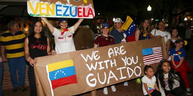 People hold signs and pose for pictures as they protest against Venezuelan President Nicolas Maduro with about 150 other people on the Ocala Downtown Square in Ocala, Fla., Wednesday, Jan. 23, 2019. The protestors in Ocala joined thousands of Venezuelans who took to the streets in Caracas, Venezuela, Wednesday, answering the opposition's call for a nationwide protest to rid Maduro from the office. (Bruce Ackerman/Star-Banner via AP)