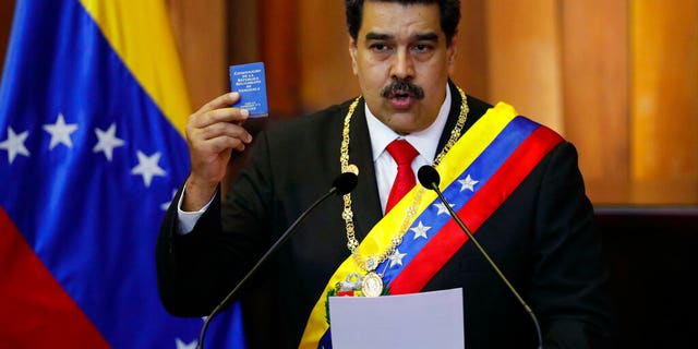 In this Jan. 10, 2019, file photo, Venezuela's President Nicolas Maduro holds up a small copy of the constitution as he speaks during his swearing-in ceremony at the Supreme Court in Caracas, Venezuela.