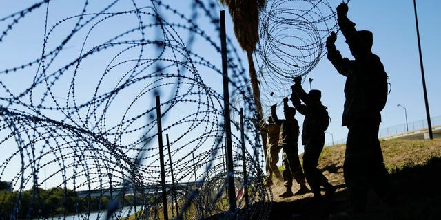 FILE - In this Nov. 16, 2018, file photo, members of the U.S. military install multiple tiers of concertina wire along the banks of the Rio Grande near the Juarez-Lincoln Bridge at the U.S.-Mexico border in Laredo, Texas. Acting Defense Secretary Pat Shanahan says the U.S. will be sending "several thousand" more American troops to the southern border to provide additional support to Homeland Security. He says the troops will mainly be used to install additional wire barriers and provide increased surveillance of the area. (AP Photo/Eric Gay, File)