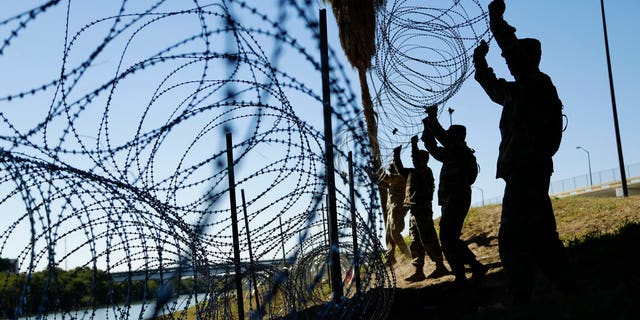 FILE - In this Nov. 16, 2018, file photo, members of the U.S. military install multiple tiers of concertina wire along the banks of the Rio Grande near the Juarez-Lincoln Bridge at the U.S.-Mexico border in Laredo, Texas. Acting Defense Secretary Pat Shanahan says the U.S. will be sending