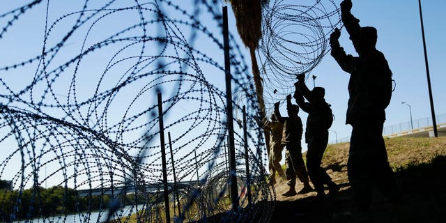 FILE - In this Nov. 16, 2018, file photo, members of the U.S. military install multiple tiers of concertina wire along the banks of the Rio Grande near the Juarez-Lincoln Bridge at the U.S.-Mexico border in Laredo, Texas. Acting Defense Secretary Pat Shanahan says the U.S. will be sending "several thousand" more American troops to the southern border to provide additional support to Homeland Security. He says the troops will mainly be used to install additional wire barriers and provide increased surveillance of the area. (AP Photo/Eric Gay, File)