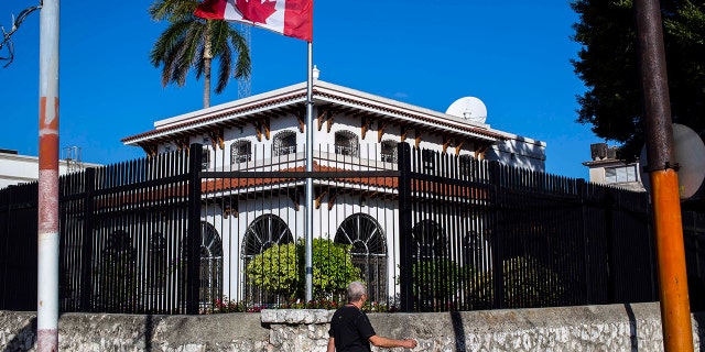 In this April 17, 2018 file photo, a man walks beside Canada's embassy in Havana, Cuba. Canada announced Wednesday, Jan. 30, 2019, it is removing up to half of the Canadians at its embassy in Cuba after another diplomat was found to have fallen mysteriously ill.