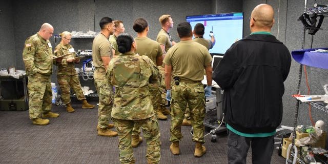 Before patient arrival, test participants with the 44th Medical Brigade studied patient information on the Medical Hands-free Unified Broadcast device. (Ashley Force, U.S. Army)