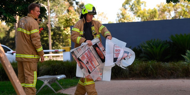 A firefighter is seen carrying a hazardous material bag into the South Korean consulate in Melbourne. (Associated Press)