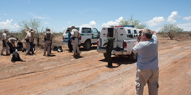 Howard Buffett photographing a border patrol apprehension in a desert area in Arizona. 