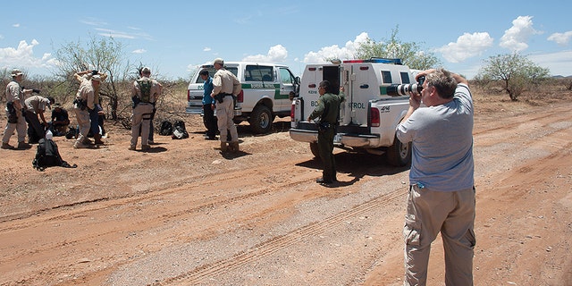 Howard Buffett photographing a border patrol apprehension in a desert area in Arizona.