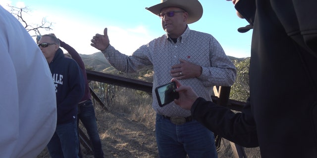 A rancher shows the congressmen and their staff a part of his ranch on the border where sticks, steel, and barbed wire separate his ranch from Mexico.
