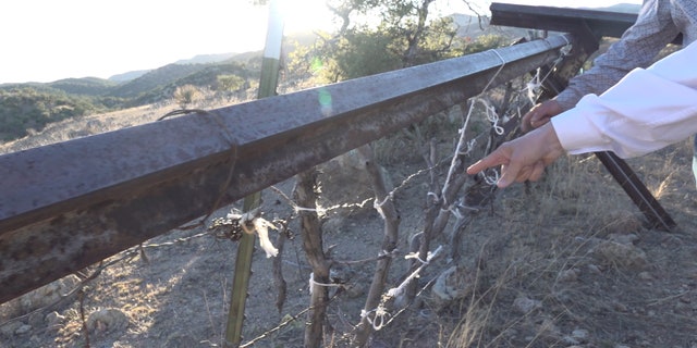 A rancher shows the congressmen and their staff a part of his ranch on the border where sticks, steel, and barbed wire separate his ranch from Mexico.