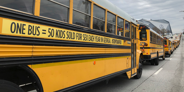 A line of school buses with new decals to draw attention to human trafficking make their way on a road in Atlanta, Wednesday, Jan. 2, 2019. The Georgia attorney general used the new decals on dozens of school buses. (AP Photo/Sarah Morgan)