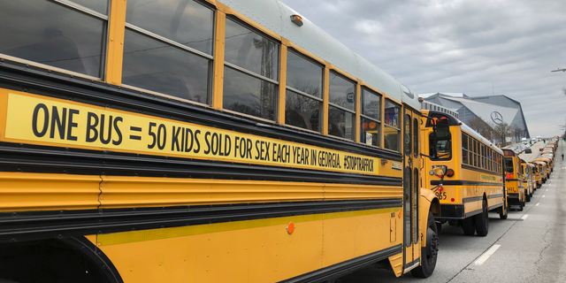 A line of school buses with new decals to draw attention to human trafficking make their way on a road in Atlanta, Wednesday, Jan. 2, 2019. The Georgia attorney general used the new decals on dozens of school buses. (AP Photo/Sarah Morgan)