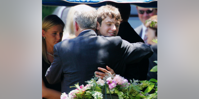In this June 29, 2006, file photo, John Ramsey hugs his son, Burke, facing the camera, at the graves of his wife, Patsy, and daughter JonBenet, during services for his wife at the St. James Episcopal Cemetery in Marietta, Ga. A $750 million defamation lawsuit filed against CBS by Burke Ramsey, the brother of JonBenet Ramsey, has been settled on Wednesday, Jan. 2, 2019. The Daily Camera reports court records show that a Michigan Circuit Court judge dismissed the lawsuit filed by Burke Ramsey in December 2016. — AP Photo/Ric Feld, File