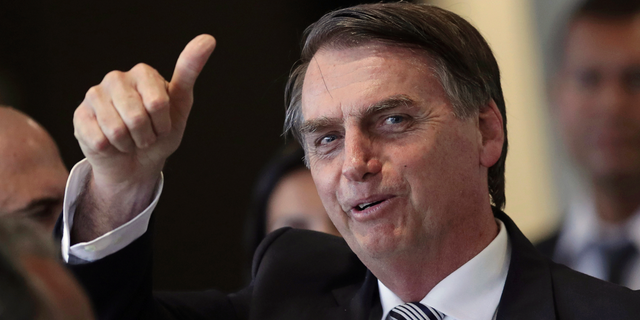 FILE - In this Dec. 4, 2018 file photo, Brazil's President-elect Jair Bolsonaro gives a thumbs up as he leaves his transition headquarters in Brasilia, Brazil. Bolsonaro will take office on Jan. 1. (AP Photo/Eraldo Peres)