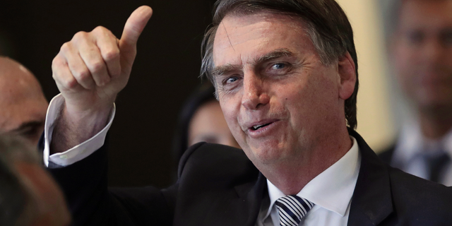 FILE - In this Dec. 4, 2018 file photo, Brazil's President-elect Jair Bolsonaro gives a thumbs up as he leaves his transition headquarters in Brasilia, Brazil. Bolsonaro will take office on Jan. 1. (AP Photo/Eraldo Peres)