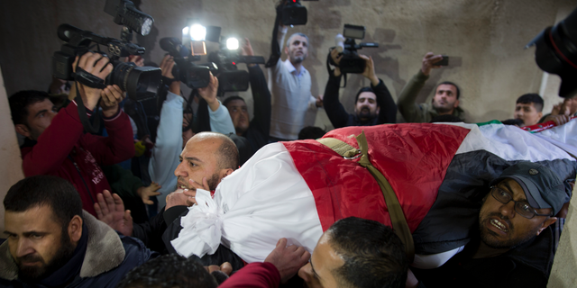 Mourners carry the body of Palestinian woman, Amal al-Taramsi, 43, who was killed by Israeli troops during Friday's protest at the Gaza Strip's border with Israel, into the family home during her funeral in Gaza City, Saturday, Jan. 12. (AP Photo/Khalil Hamra)