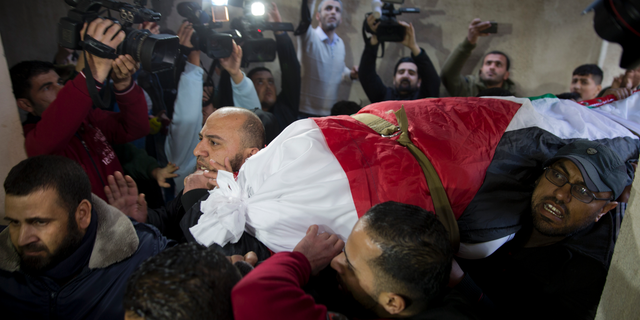 Mourners carry the body of Palestinian woman, Amal al-Taramsi, 43, who was killed by Israeli troops during Friday's protest at the Gaza Strip's border with Israel, into the family home during her funeral in Gaza City, Saturday, Jan. 12. (AP Photo/Khalil Hamra)