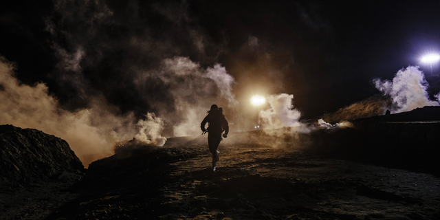 Migrants run as tear gas is thrown by U.S. Border Protection officers to the Mexican side of the border fence after they climbed the fence to get to San Diego, Calif., from Tijuana, Mexico, Tuesday, Jan. 1, 2019. Discouraged by the long wait to apply for asylum through official ports of entry, many migrants from recent caravans are choosing to cross the U.S. border wall and hand themselves in to border patrol agents. (AP Photo/Daniel Ochoa de Olza)